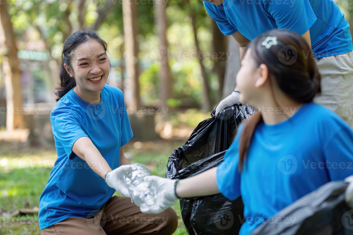 Family volunteers collecting garbage in community park nature cleanup event outdoor family activity engaging community efforts photo