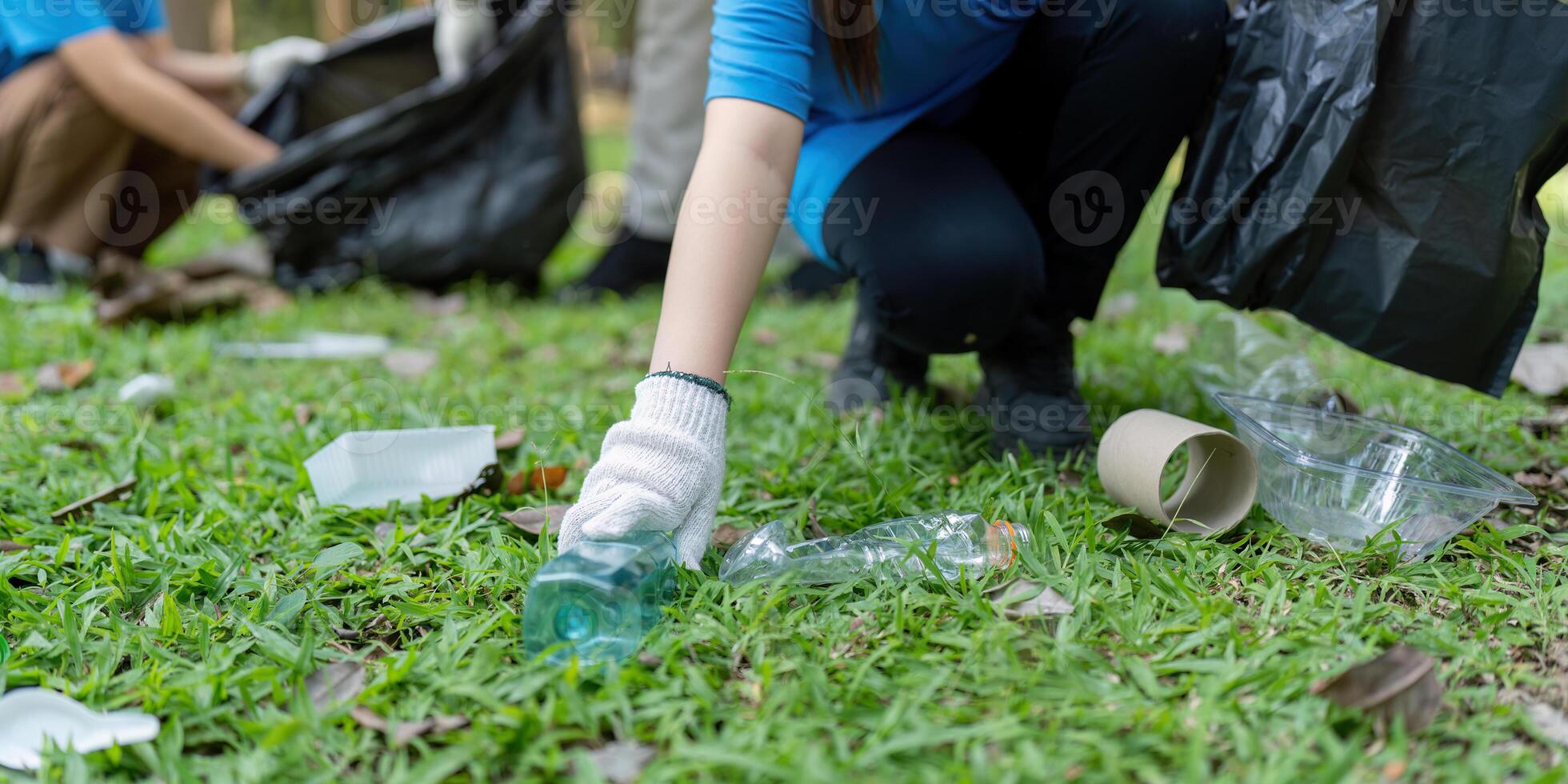 Family volunteers collect garbage in nature environmental clean-up event community effort park positive impact photo