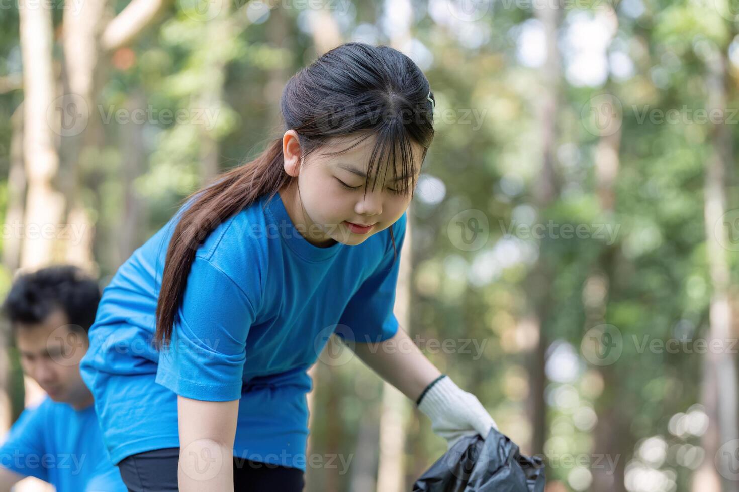Family volunteers collecting garbage in nature community clean up event outdoor activity positive environment photo