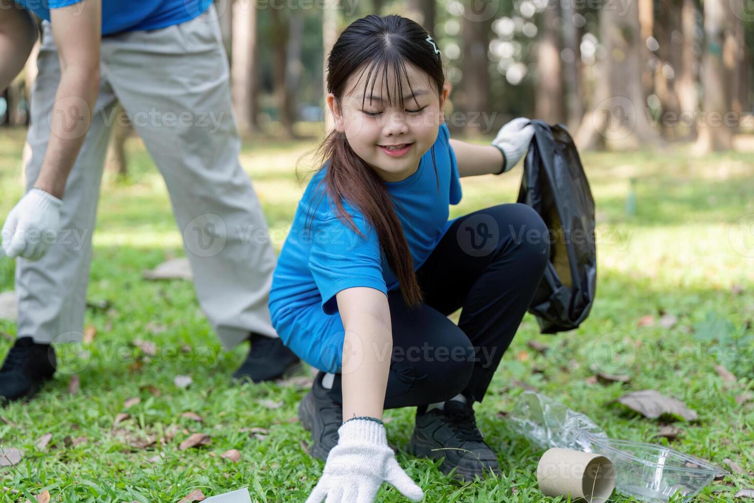Family volunteers collecting garbage in nature outdoor clean up event community service initiative photo