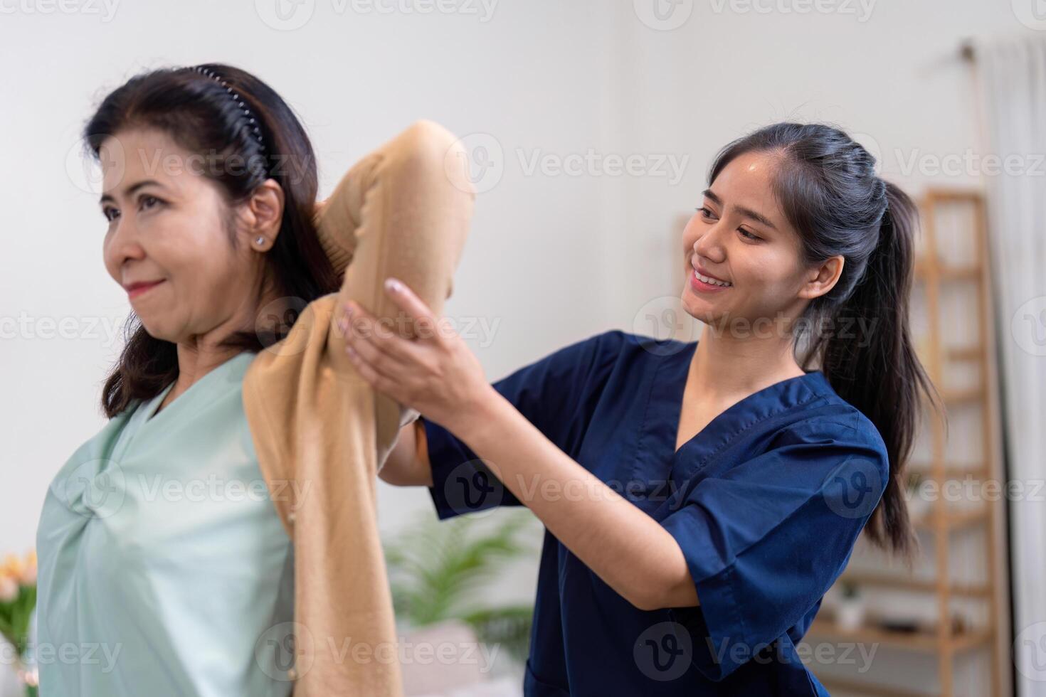 Assisting elderly woman with clothing change home setting healthcare interaction indoor environment caring viewpoint compassion theme photo