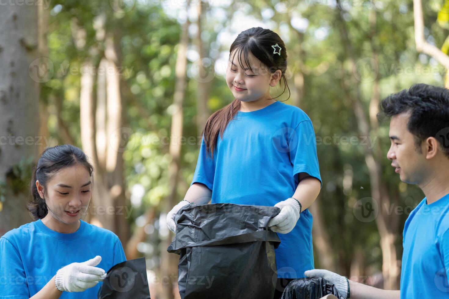 Family volunteers collect garbage in nature community clean up event outdoor activity joyful environment photo