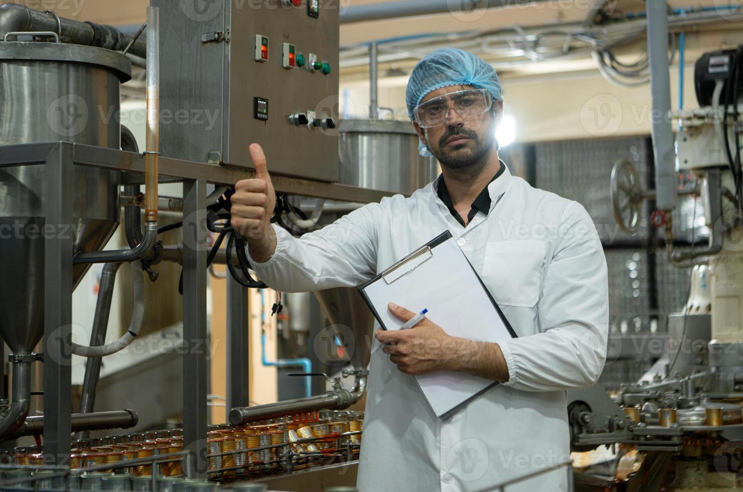Portrait of production control supervisor inspects and controls the operation of each step in the production line of a canned fish factory photo