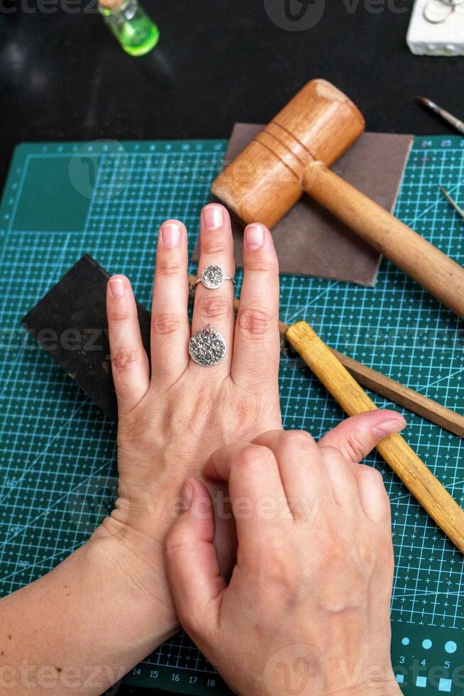 Female hands with a silver ring and pendant in moon shape on a background of jewelry workplace. photo