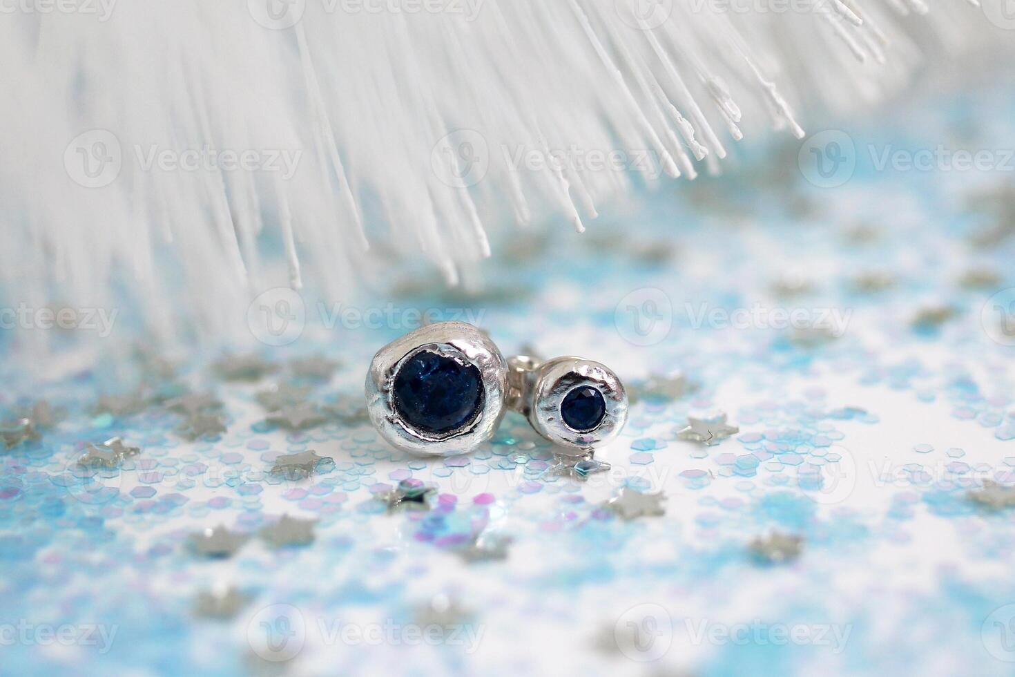 hecho a mano redondo plata pendientes con oscuro azul piedras preciosas en blanco brillante Navidad antecedentes. foto