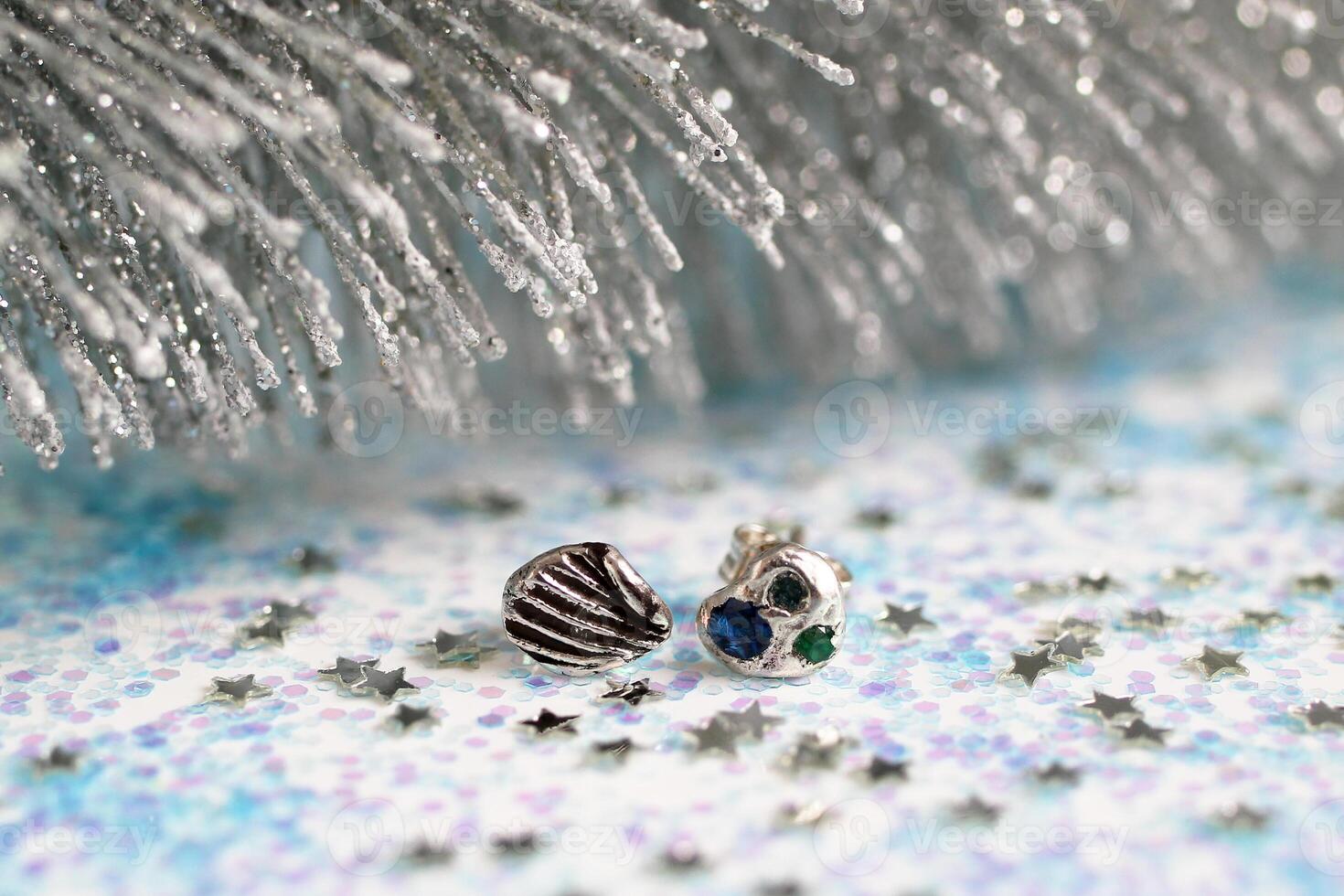 Handmade stylish silver earrings with gemstones on white Christmas glitter background. photo