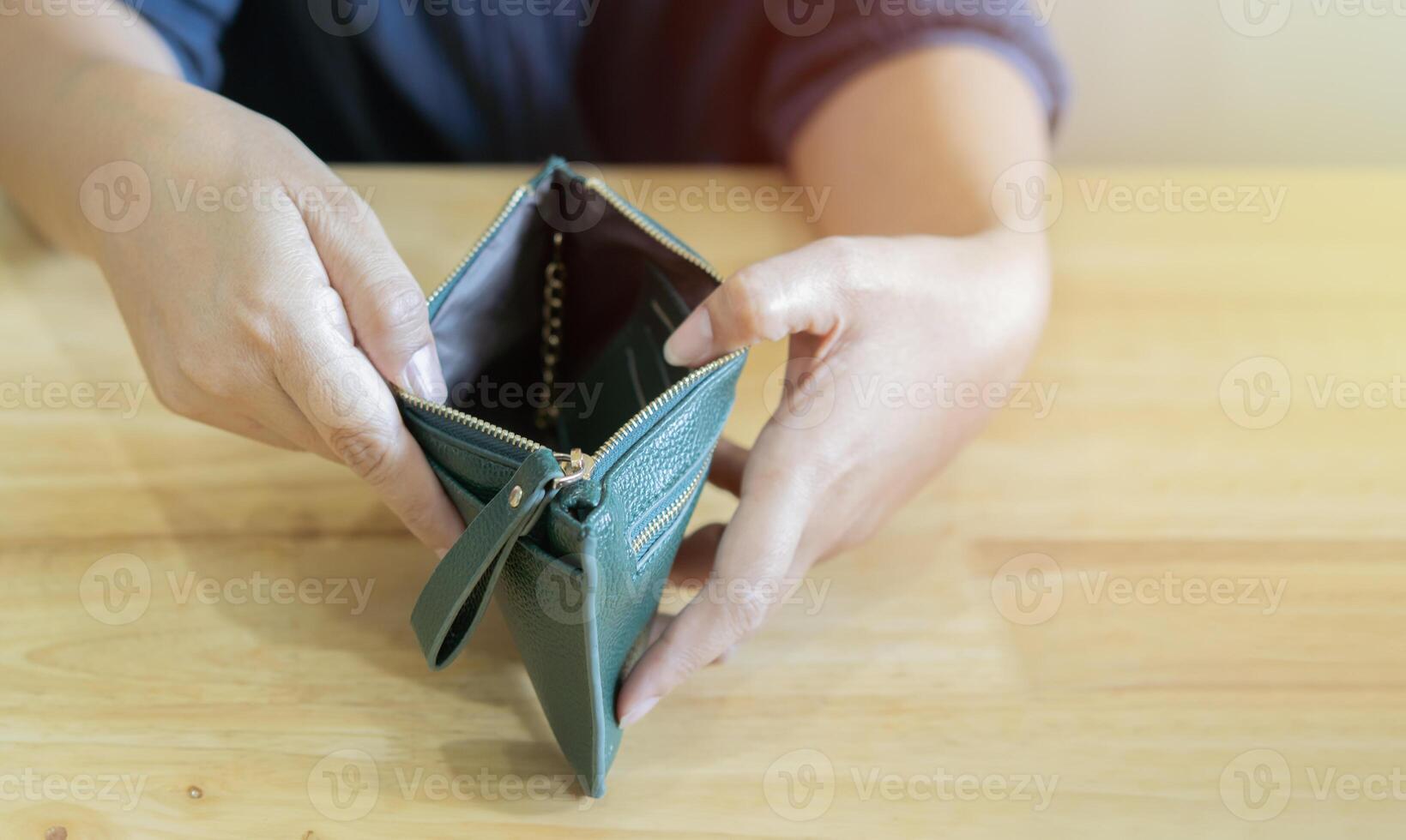 Empty wallet in the hands of woman over wooden table. Cost control expenses poverty in concept. photo
