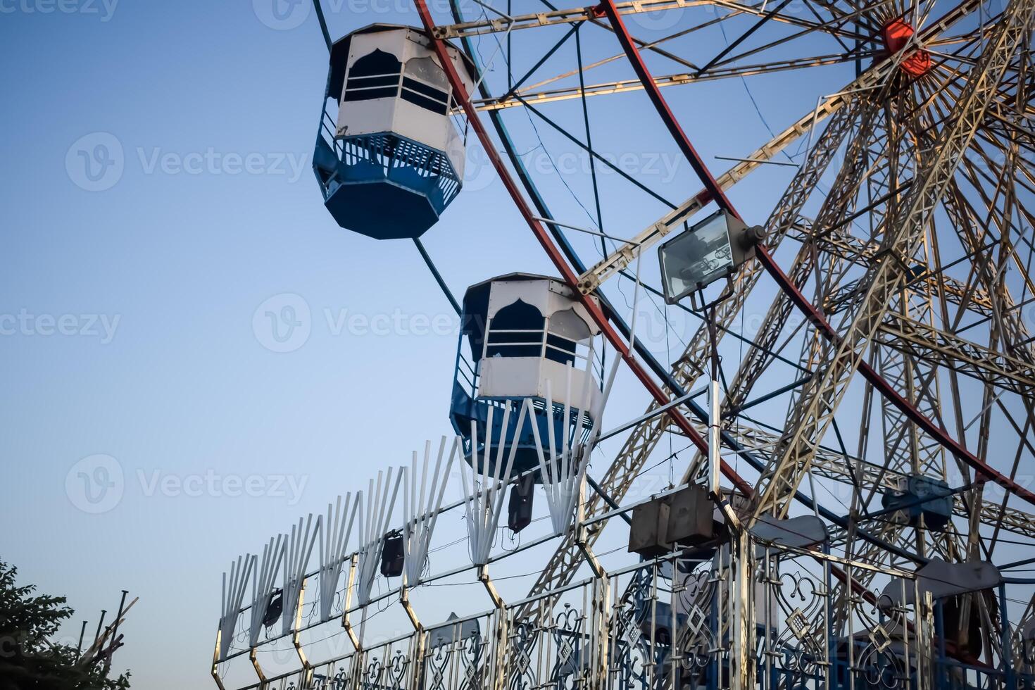 Closeup of multi-coloured Giant Wheel during Dussehra Mela in Delhi, India. Bottom view of Giant Wheel swing. Ferris wheel with colourful cabins during evening time. photo