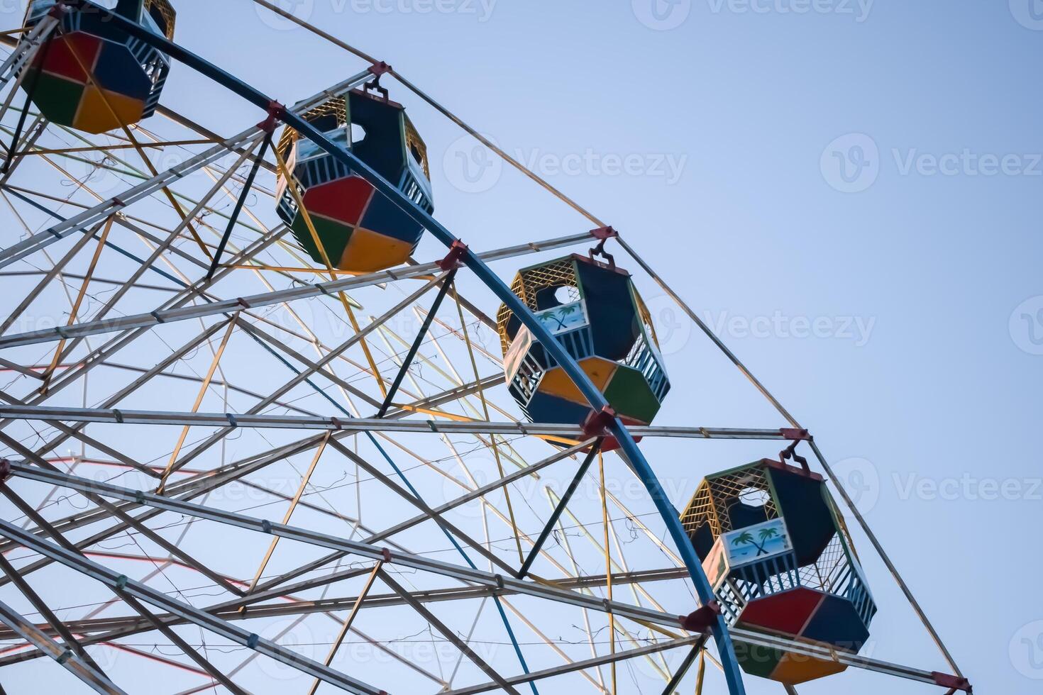 Closeup of multi-coloured Giant Wheel during Dussehra Mela in Delhi, India. Bottom view of Giant Wheel swing. Ferris wheel with colourful cabins during evening time. photo