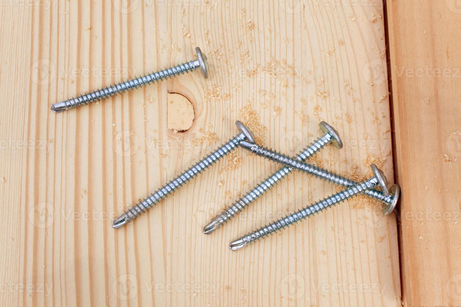 five steel screws on a wooden plank photo