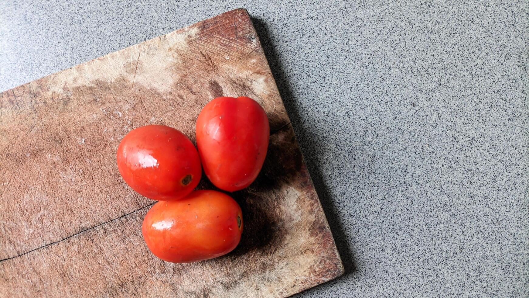 Close up of three tomatoes on a cutting board. photo