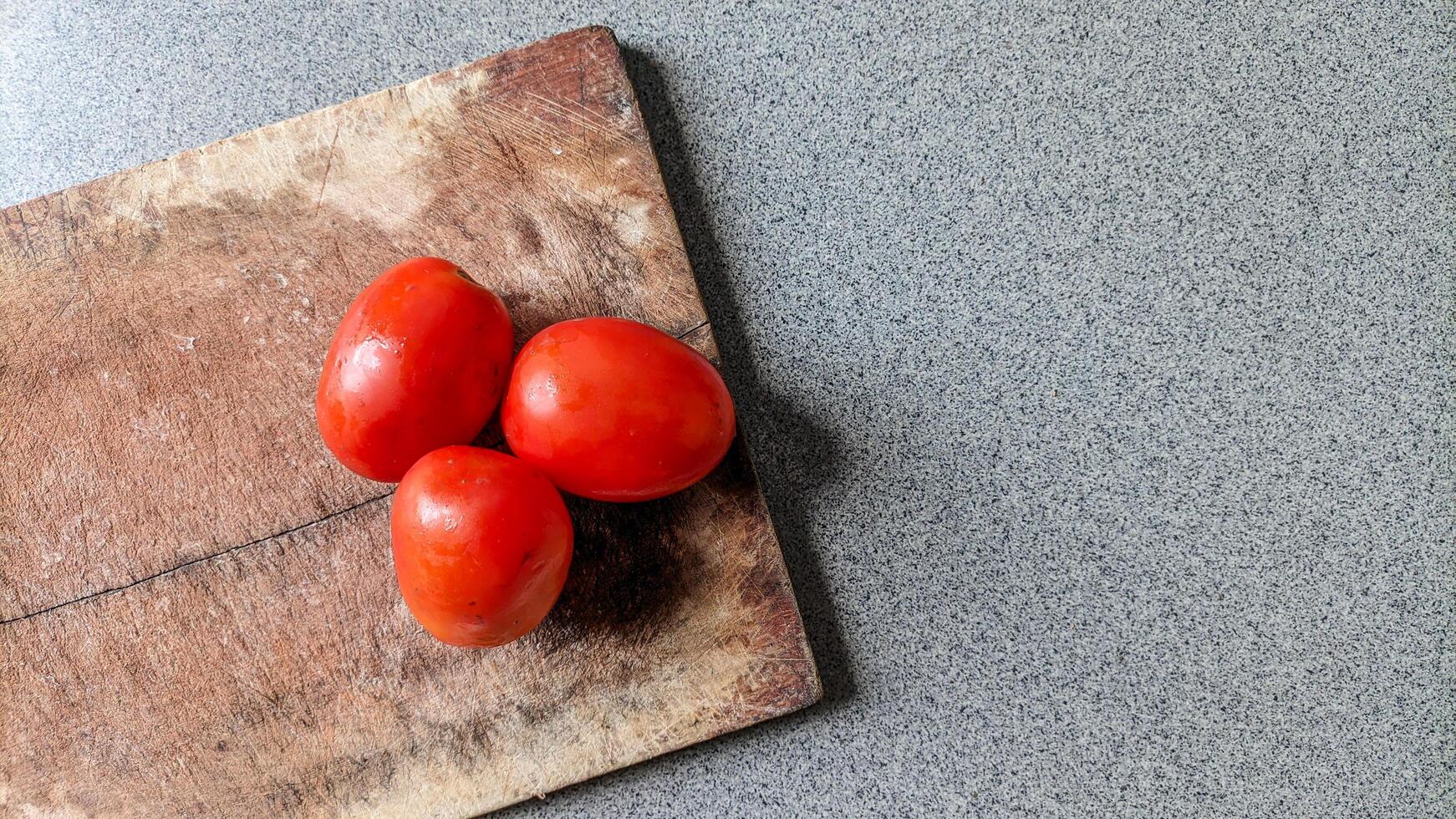 Close up of three tomatoes on a cutting board. photo