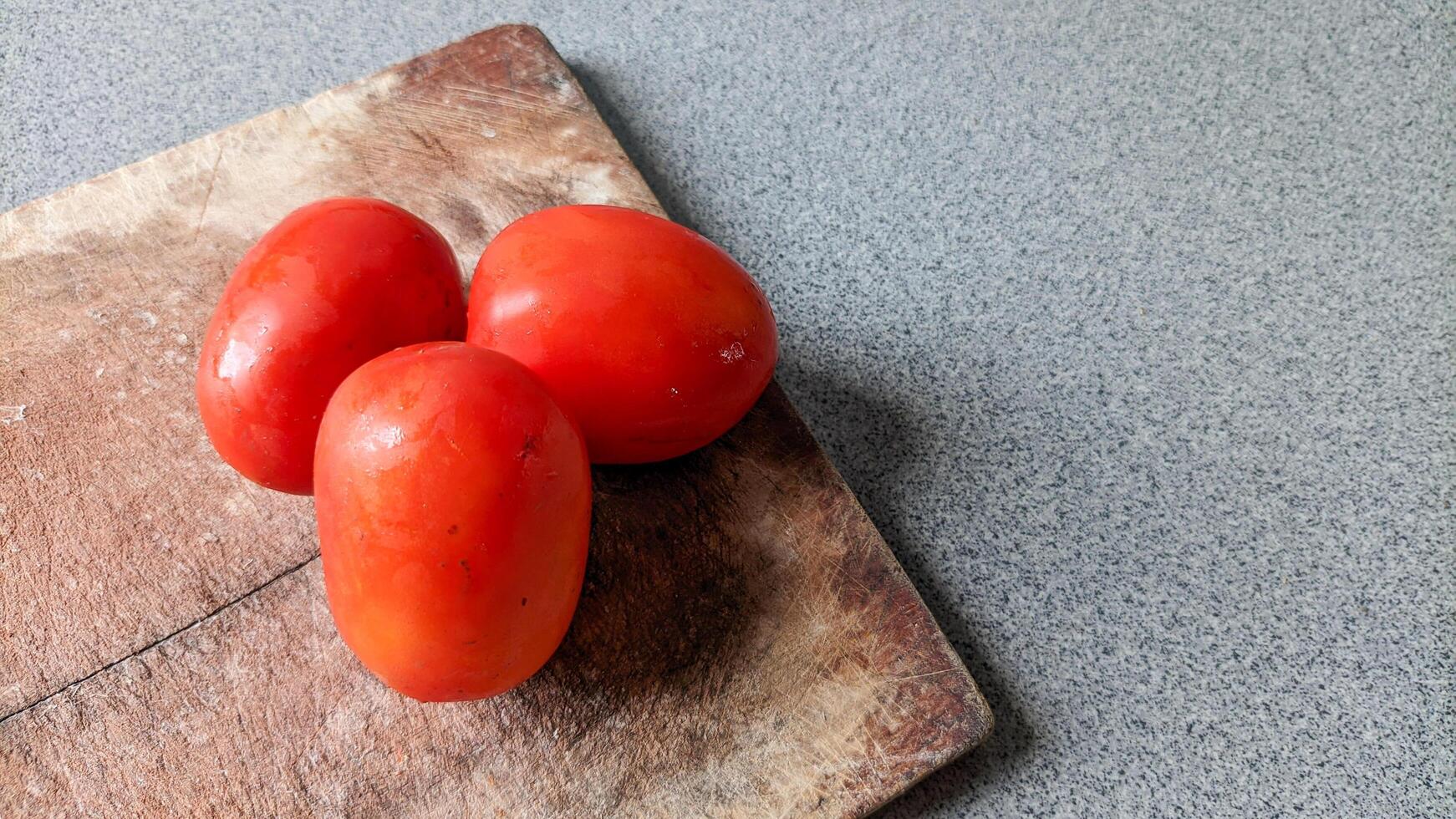 Close up of three tomatoes on a cutting board. photo