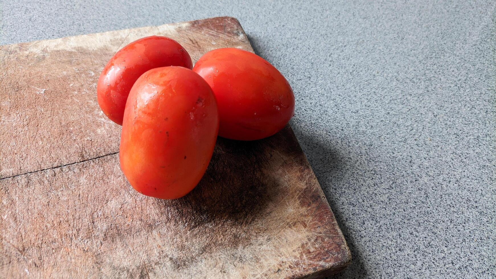 Close up of three tomatoes on a cutting board. photo