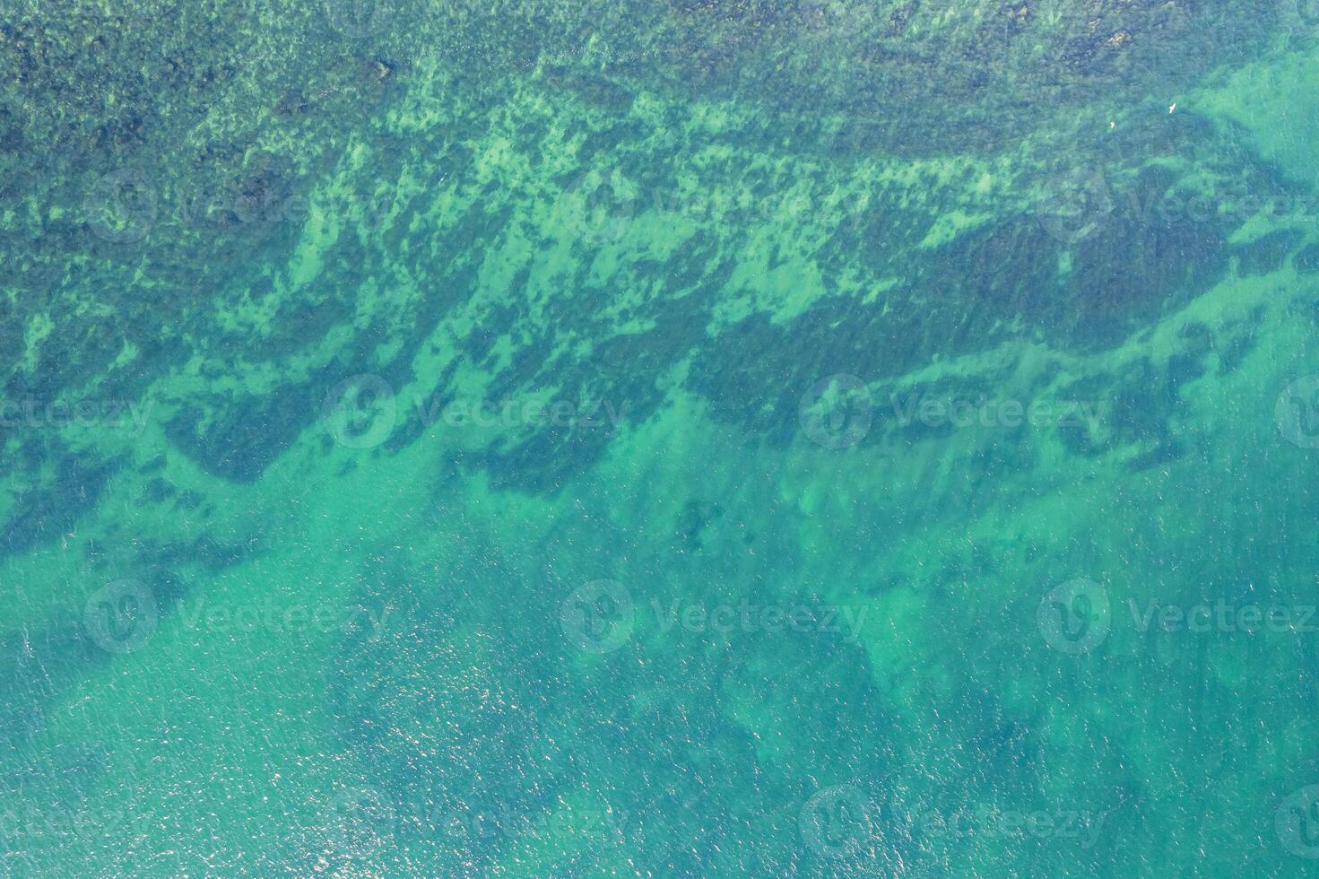 close-up aerial drone top view of water and seabed at the shore of a beach, textured background marine concept photo