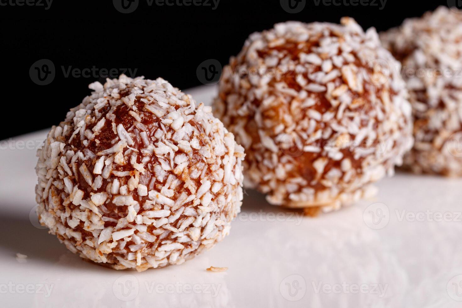 Beautiful sweets with coconut on a white plate on a black background photo