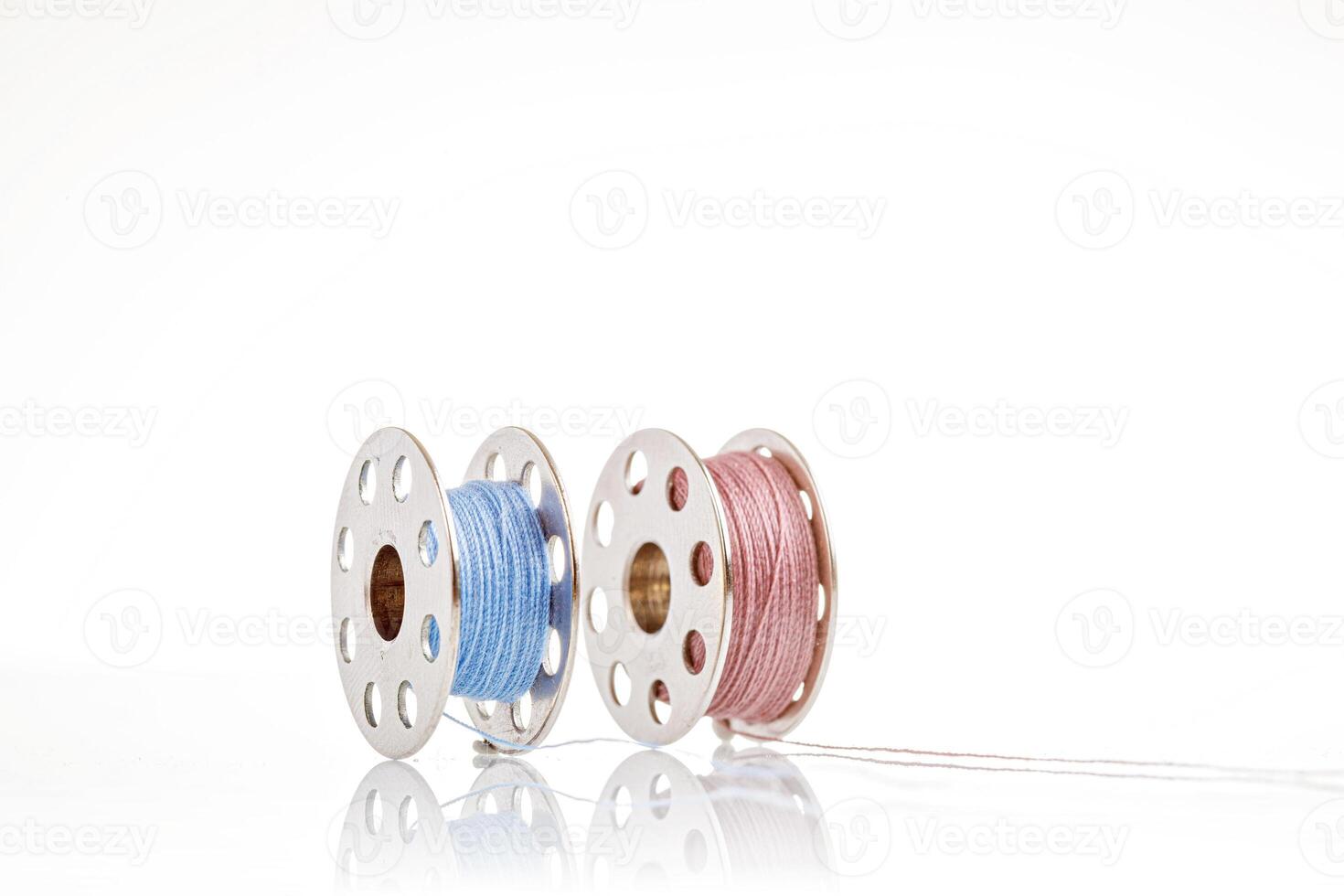 spools of blue and pink thread on a white background photo