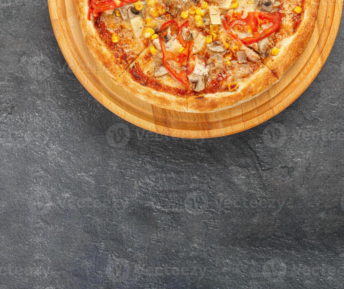 delicious pizza with chicken, mushrooms, cheese, tomatoes and corn on a concrete background photo