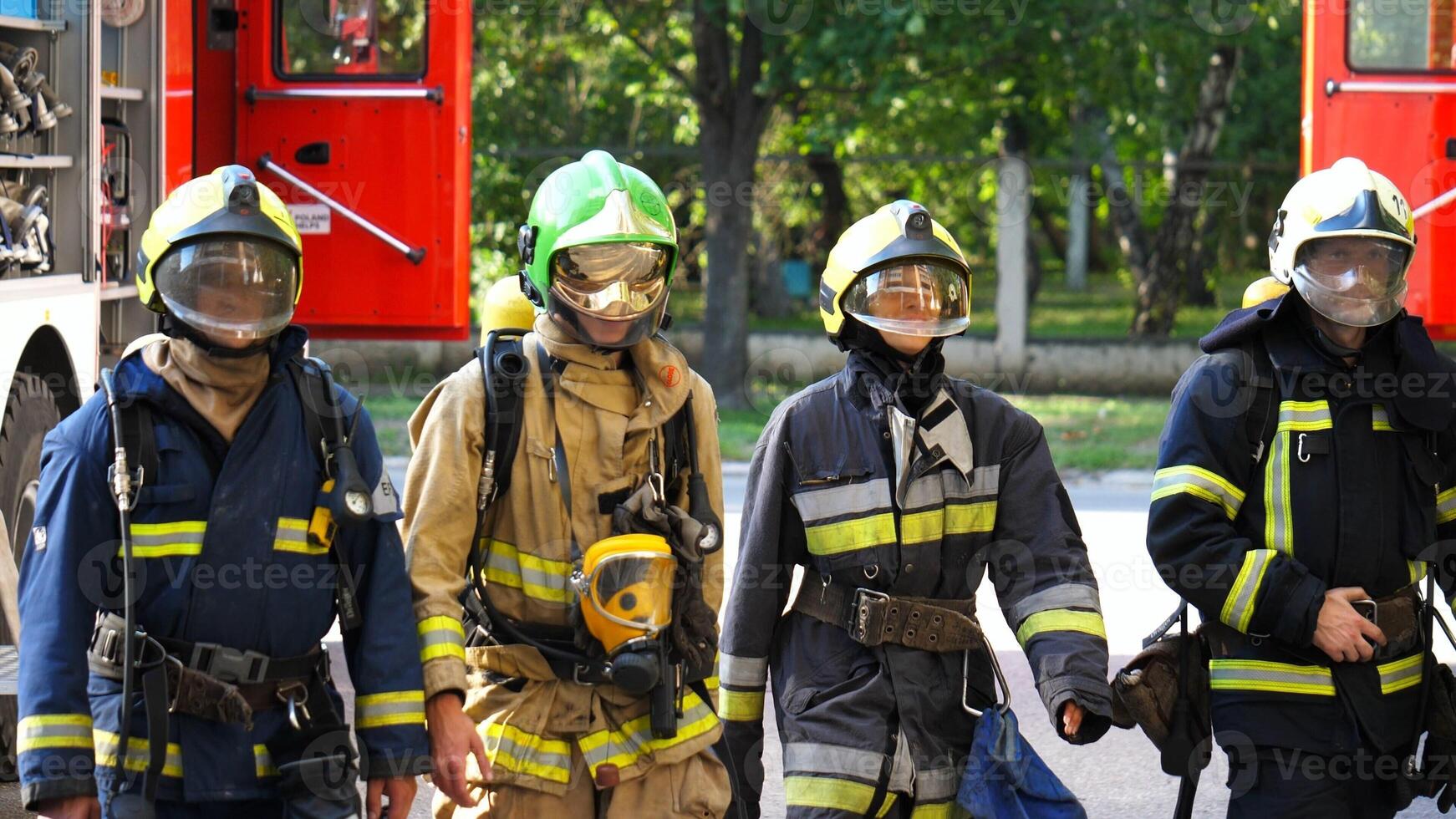 Tired male and female fireguards in full equipment walk after putting out the fire. Young exhausted firemen and firewoman go after extinguishing emergency. Saving lives and heroic profession concept photo
