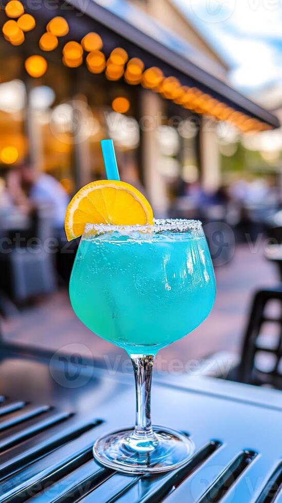 Refreshing Blue Lagoon mocktail served in a sunny outdoor setting with vibrant ambiance. photo