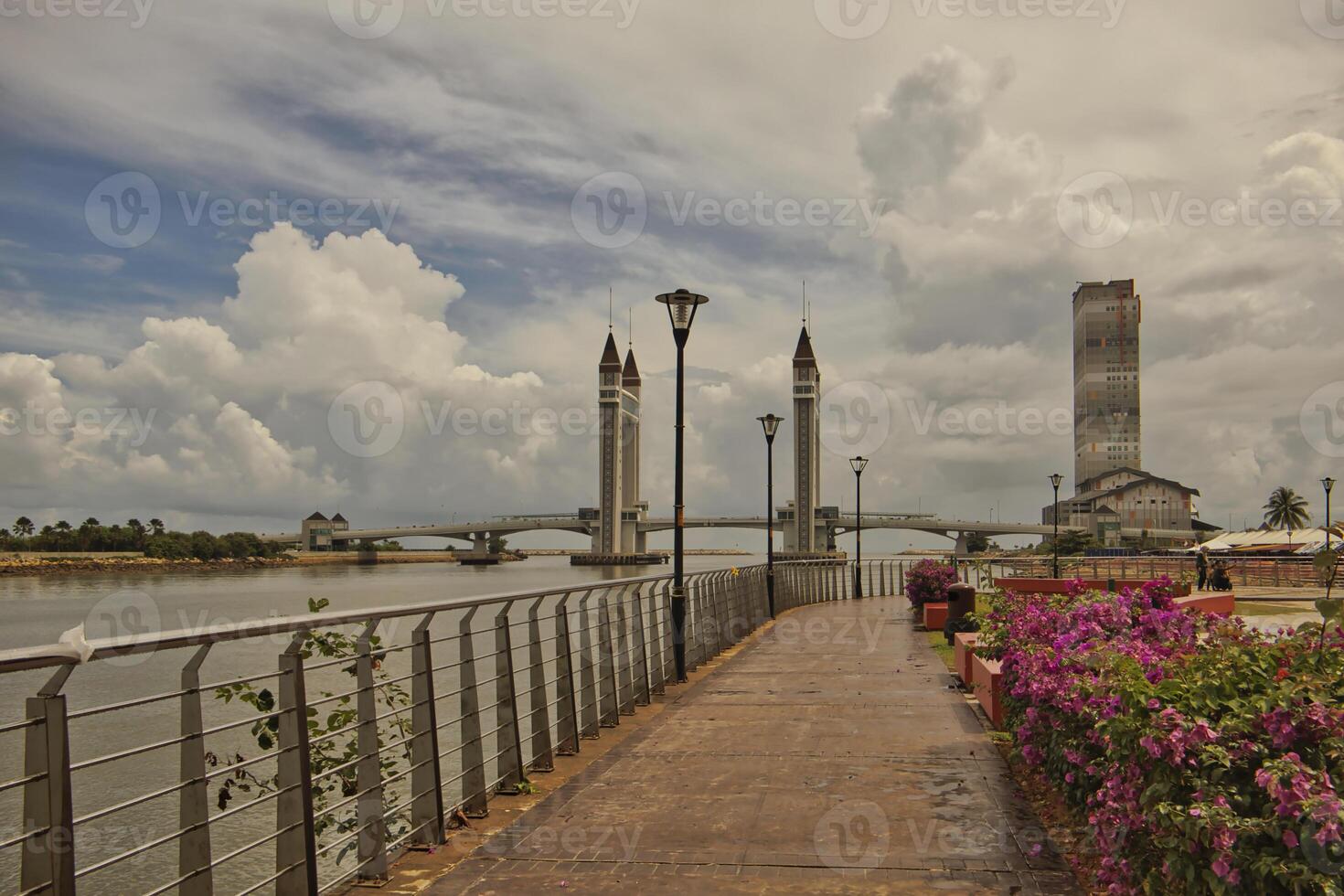 A stunning photogenic Kuala Terengganu drawbridge under a dramatic cloudy sky with structure featuring twin towers and a modern design that nestled against the ocean below. photo