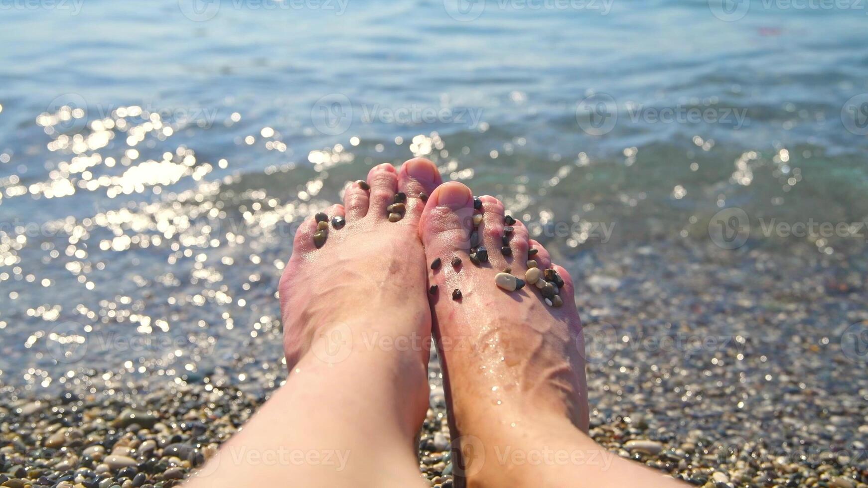 close up Female feet on the background of the sea surf, on the beach with small pebbles, concept vacation at the sea, relax photo