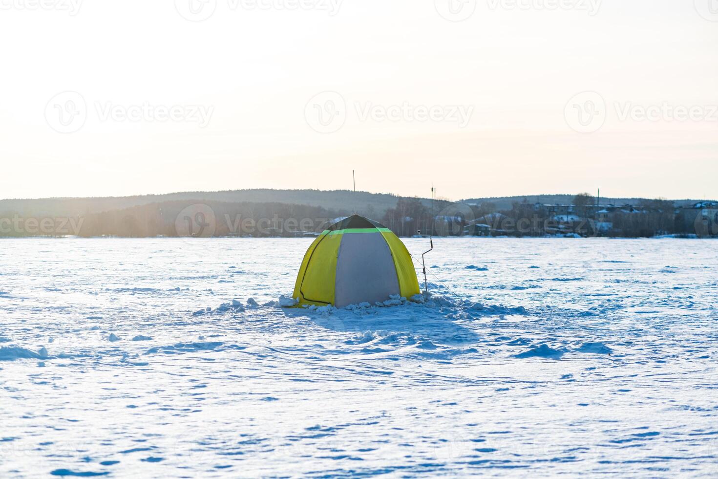 Ice fishing. Tent and fishing auger, ice auger on snowy lake in winter, winter pastime, hobby, relaxation photo
