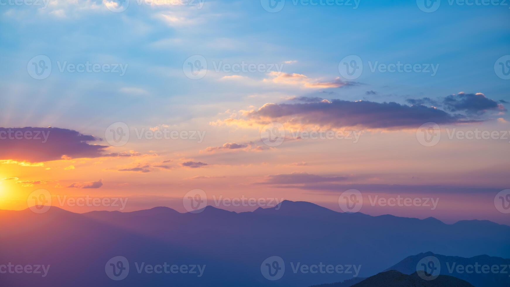 The setting sun over the mountains, the beautiful sun's rays shine through the clouds, the natural background, freedom, tranquility and peace photo