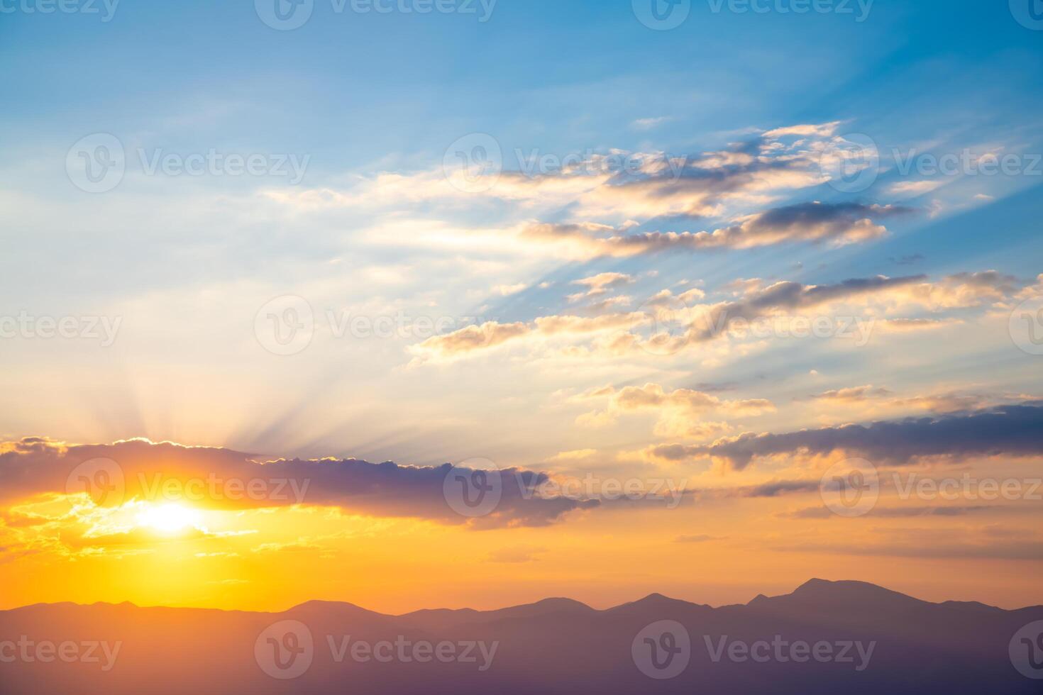 The setting sun over the mountains, the beautiful sun's rays shine through the clouds, the natural background, freedom, tranquility and peace photo