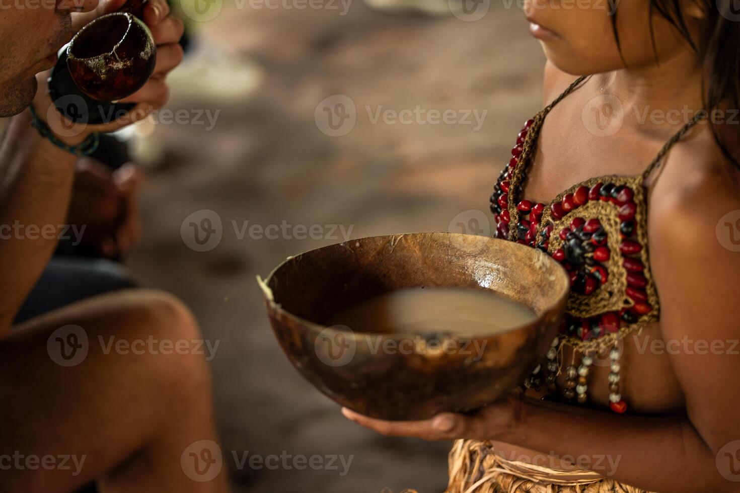 Wayuri indigenous girl offering a bowl of Chicha drink to a tourist in Ecuadorian Amazon photo