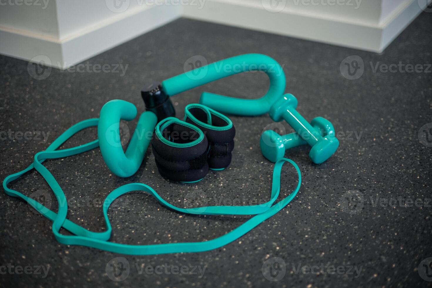 Various gym training equipment such as dumbbells, ankle weights, and resistance bands on gym floor photo