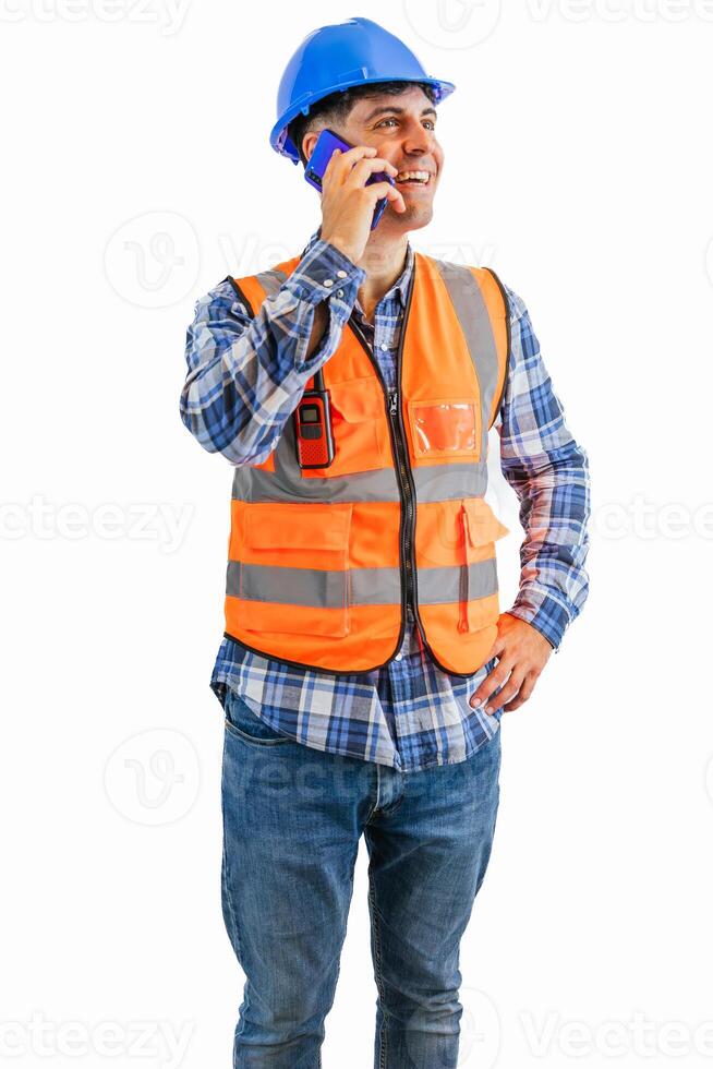 vertical sonriente construcción trabajador haciendo llamada con su teléfono inteligente vistiendo naranja chaleco y casco foto