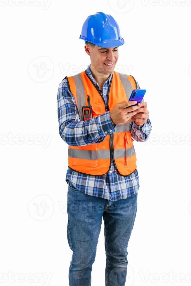 vertical Smiling construction worker texting on his smartphone wearing orange vest and safety helmet photo