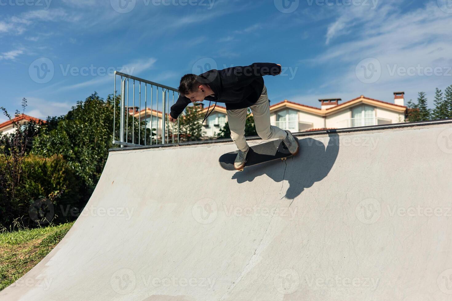 Skater dropping into half-pipe at skate park on a sunny day photo