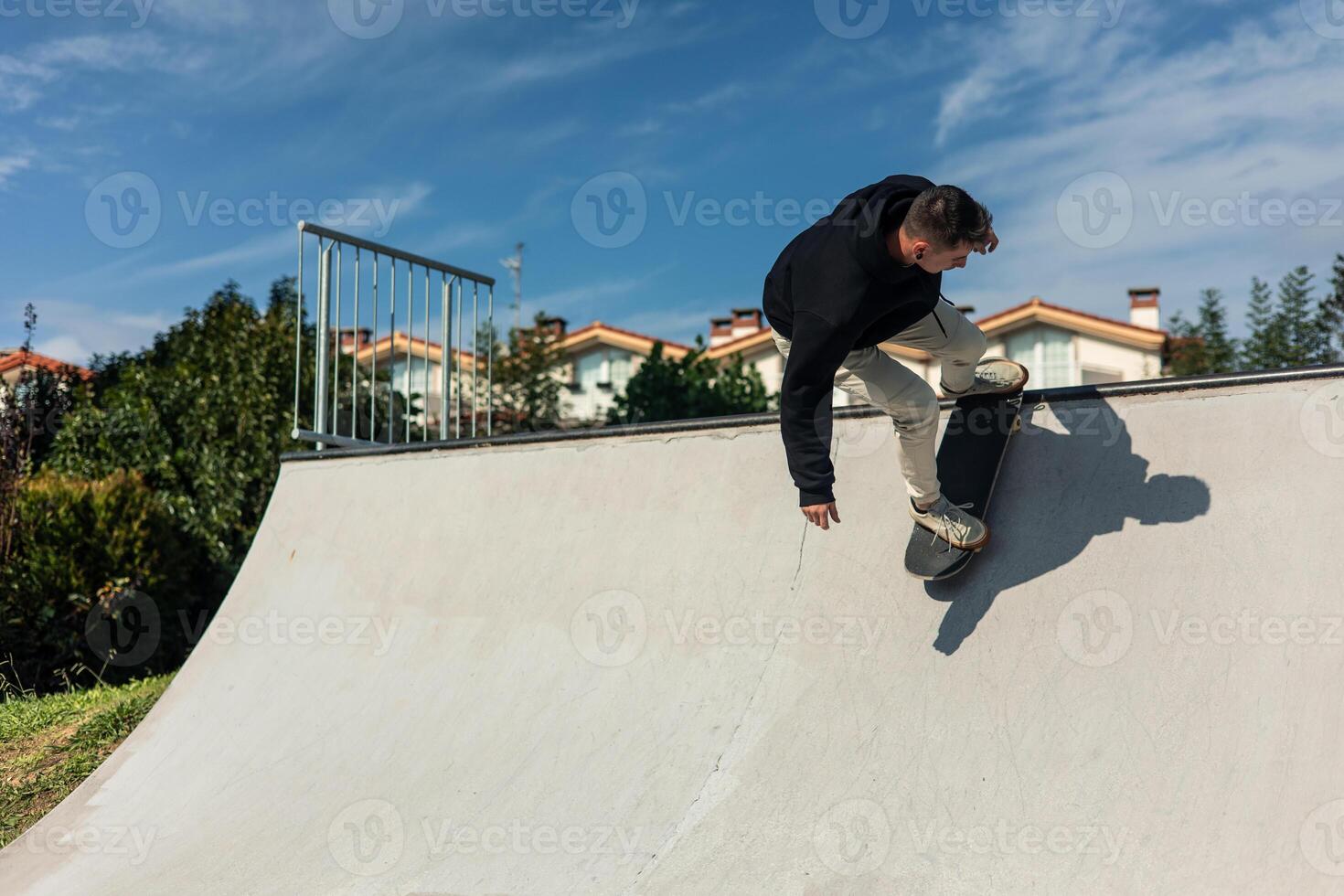 Skater riding down half-pipe at skate park on a bright sunny day photo