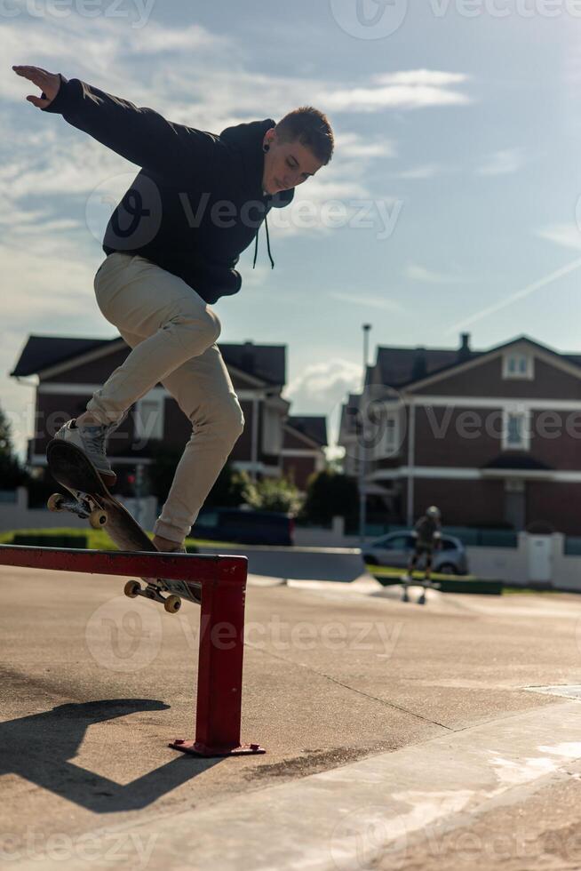 vertical Skater grinding a rail at skate park on a sunny afternoon photo