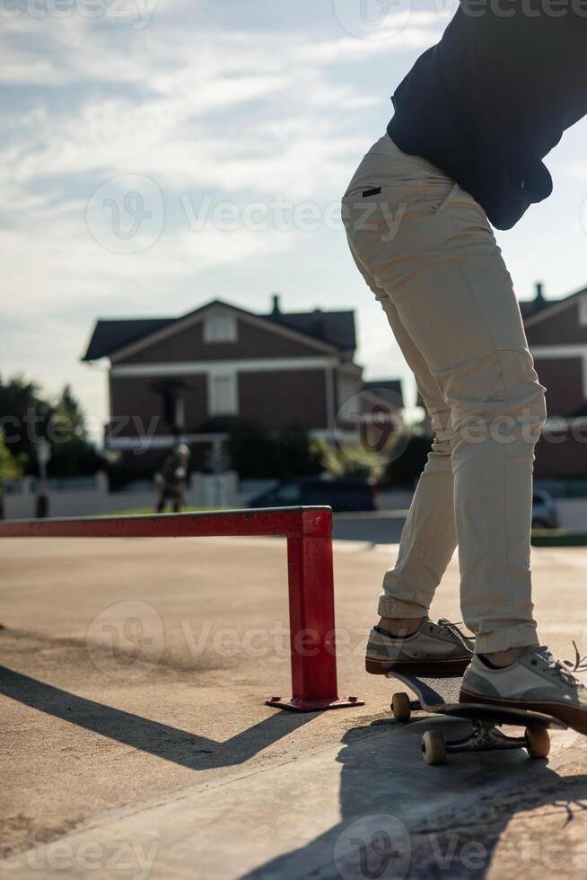 vertical Close-up of unrecognizable skater next to red rail after grinding at skate park photo