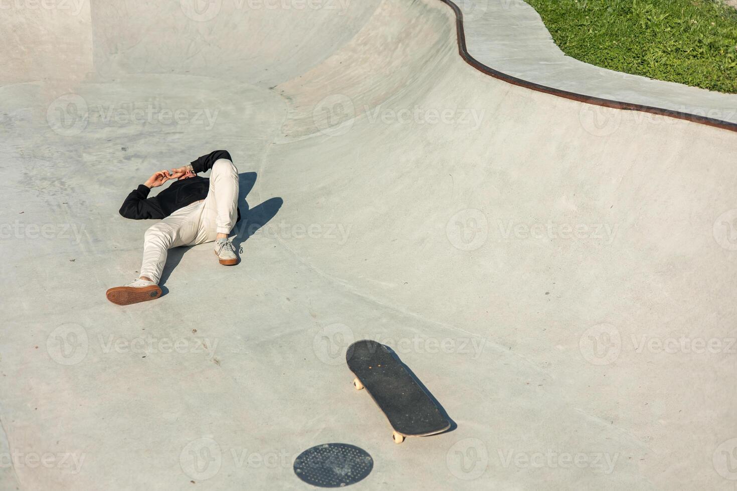 Hurt skater lying on the ground after falling from skateboard due to hitting a manhole cover photo