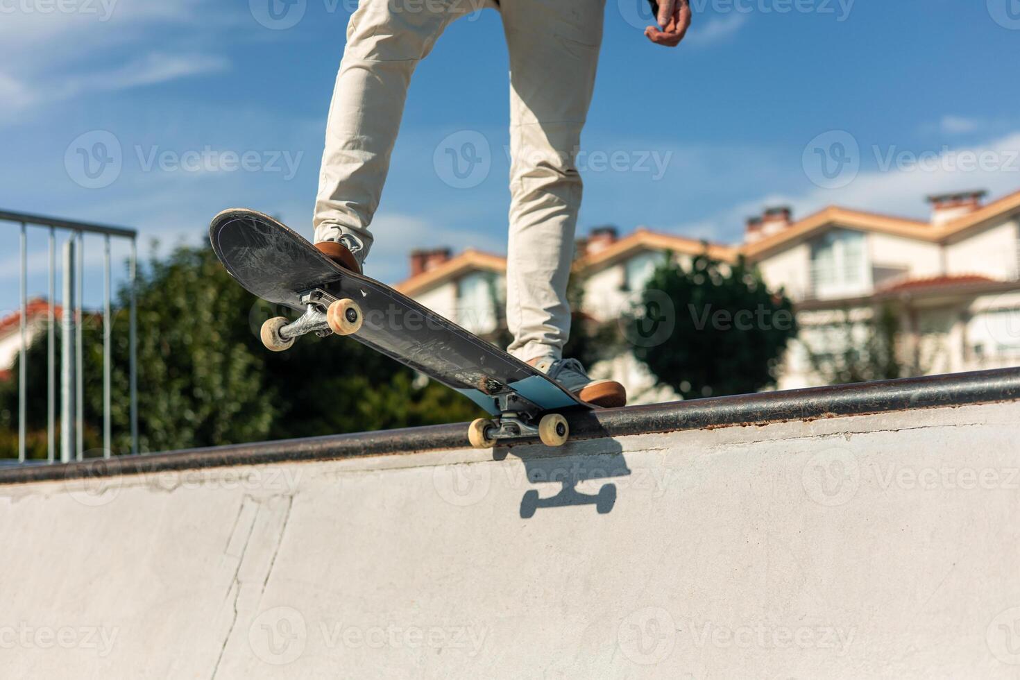Close-up of a skater's legs on the board at the edge of the half-pipe on a sunny day photo