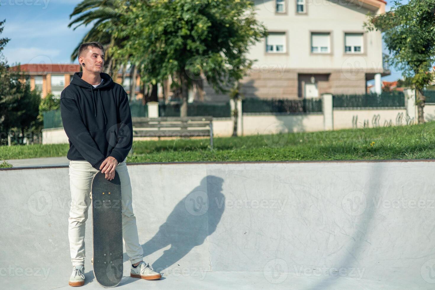 copyspace Reflective skater standing with skateboard, looking off into the distance photo