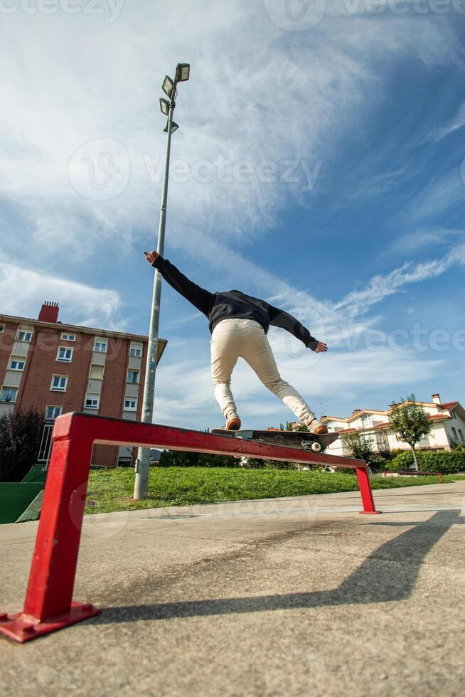 Fish-eye view of a skater grinding a rail from behind in the skate park photo