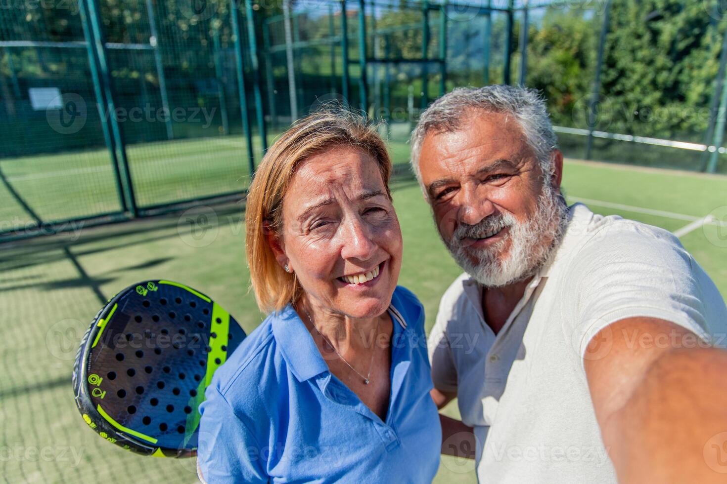 Senior padel couple taking selfie on court during match photo