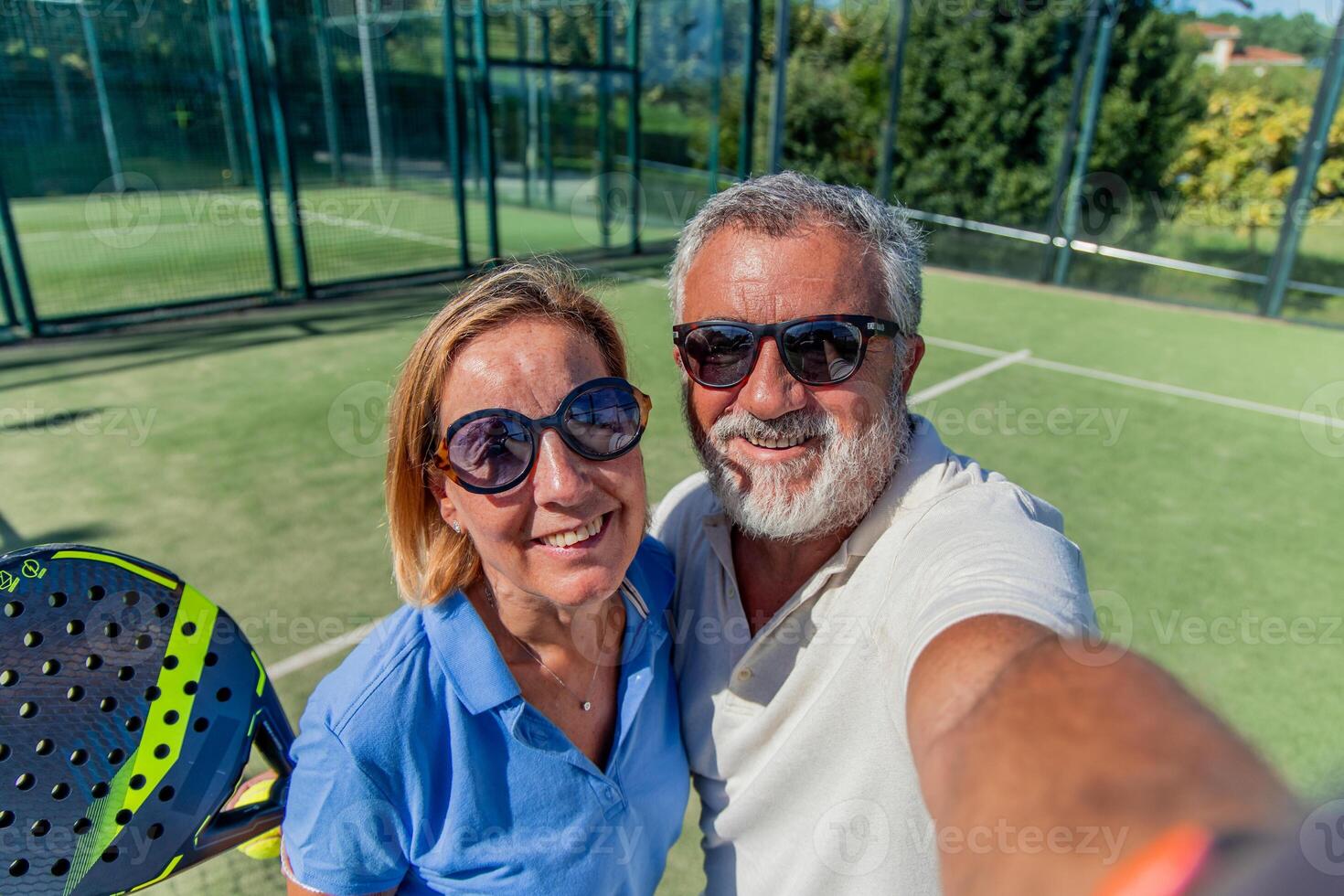 elderly padel couple with sunglasses taking selfie on court after winning match photo