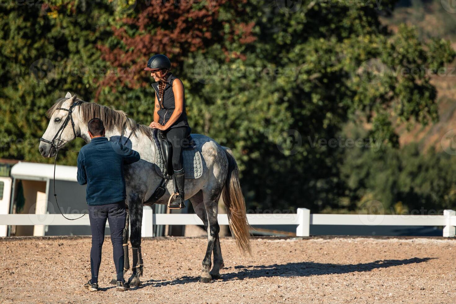 Riding instructor assists young student on horseback during a lesson at the equestrian center photo