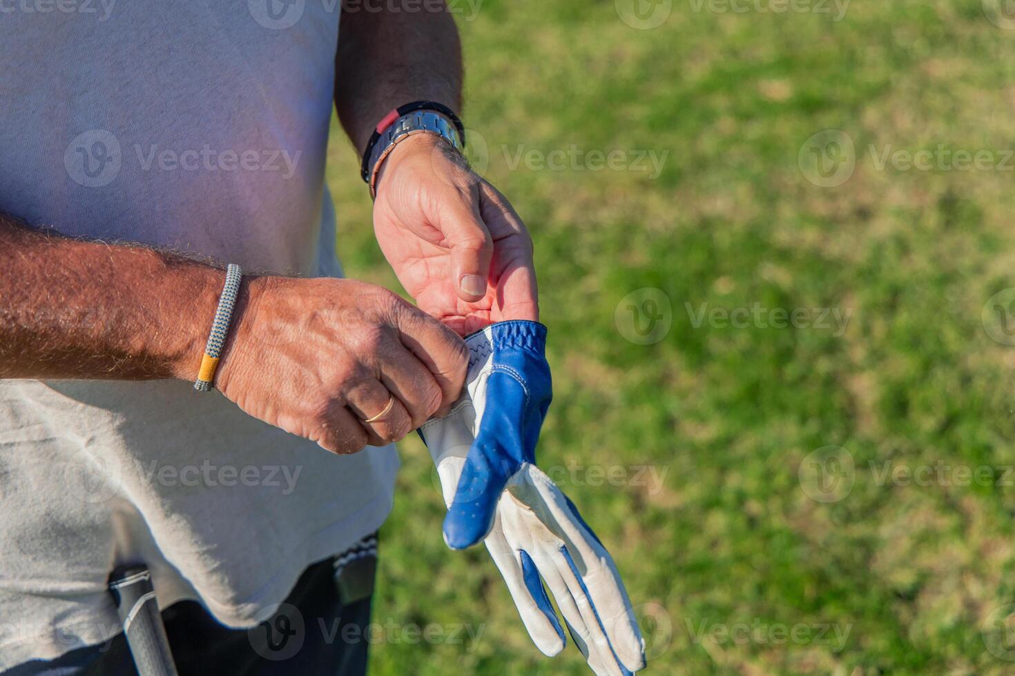closeup of senior golfer adjusting glove before starting golf game photo