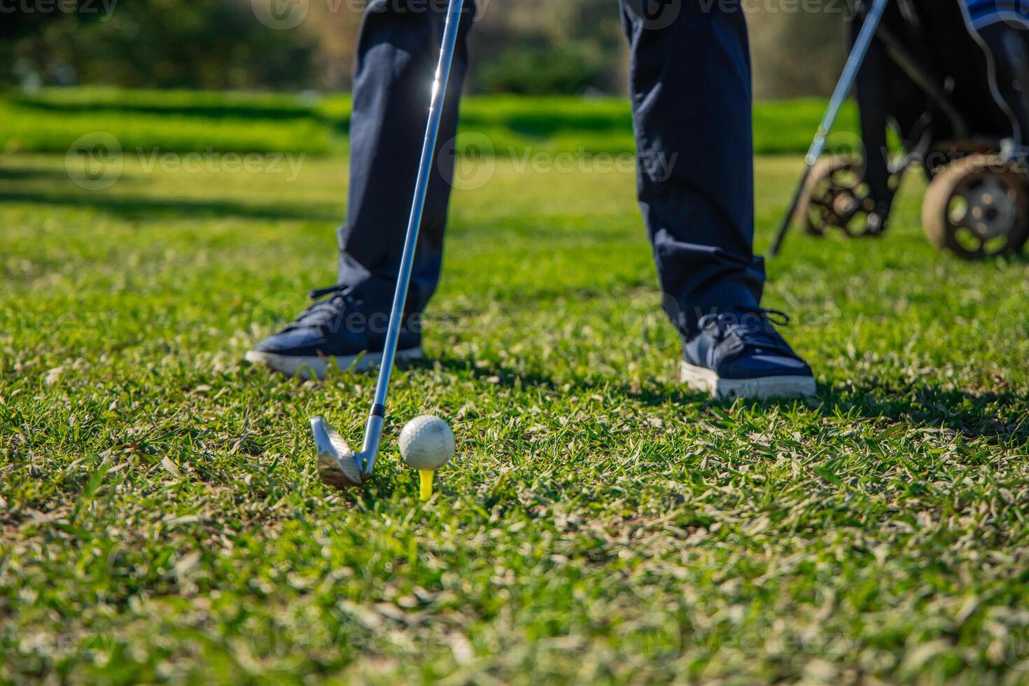 closeup of senior golfer's legs positioned with club ready to strike ball on tee photo