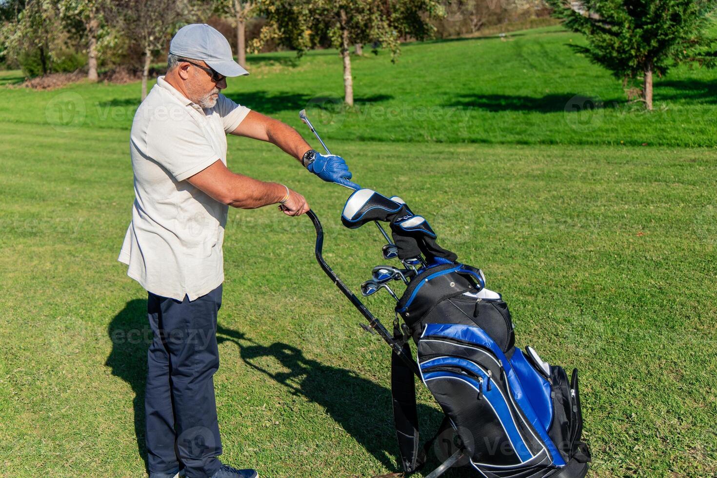 senior golfer selecting the right club from bag for next shot photo