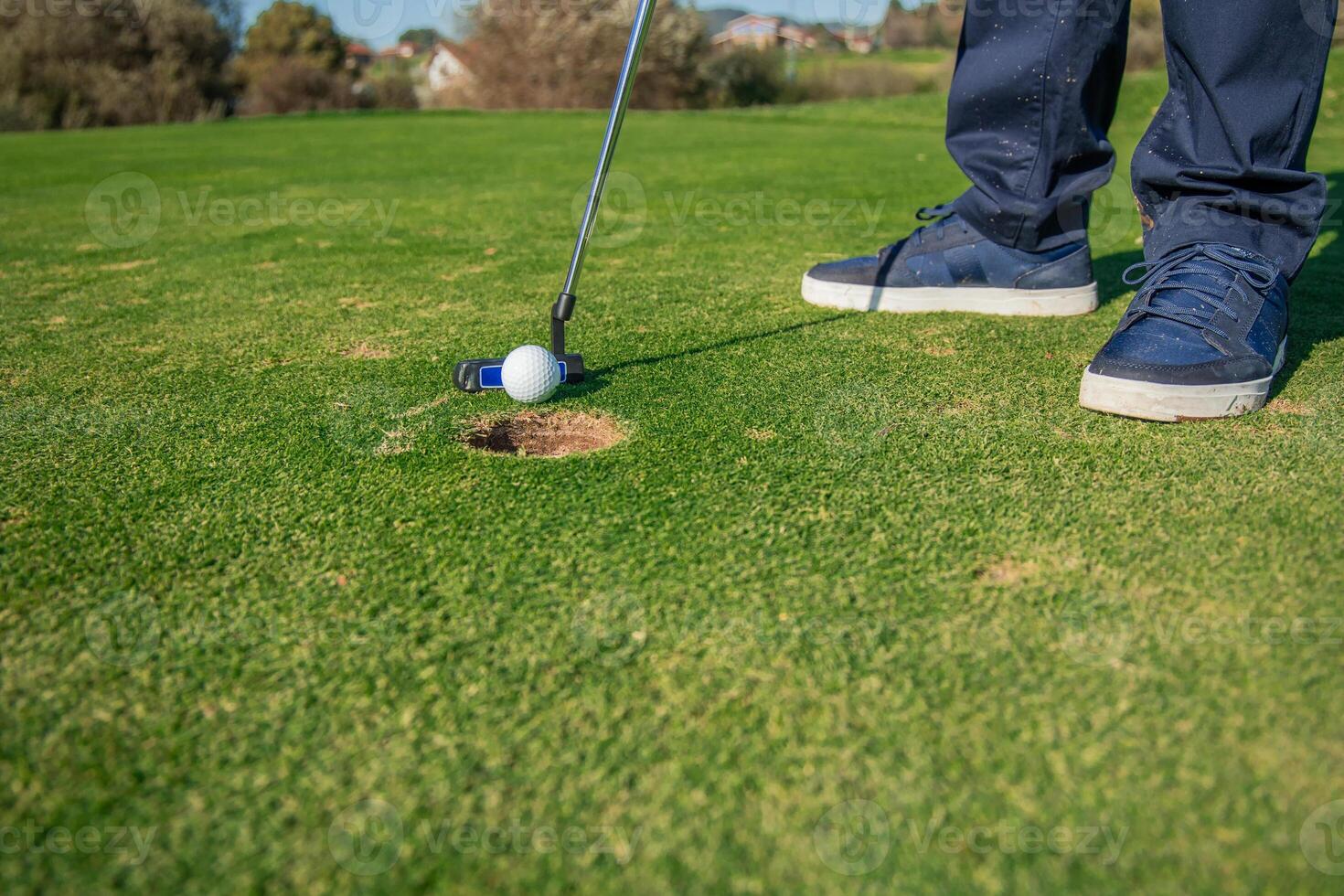 copyspace Close-up of golfer's feet striking the ball with a putter toward the hole on the green photo