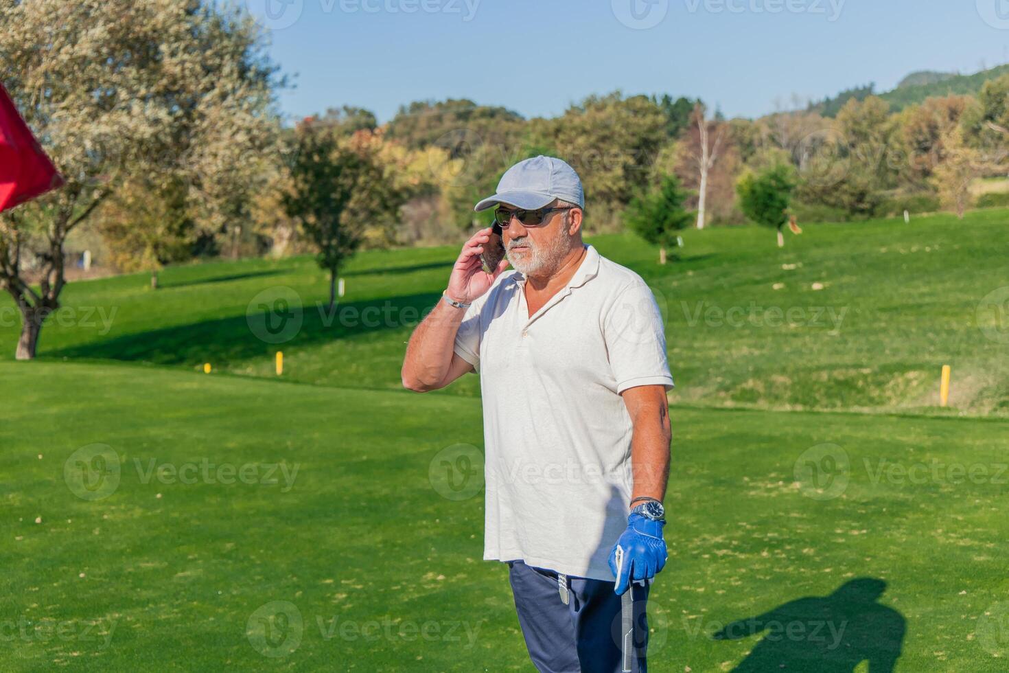copyspace senior golfer making business call with smartphone during golf game photo