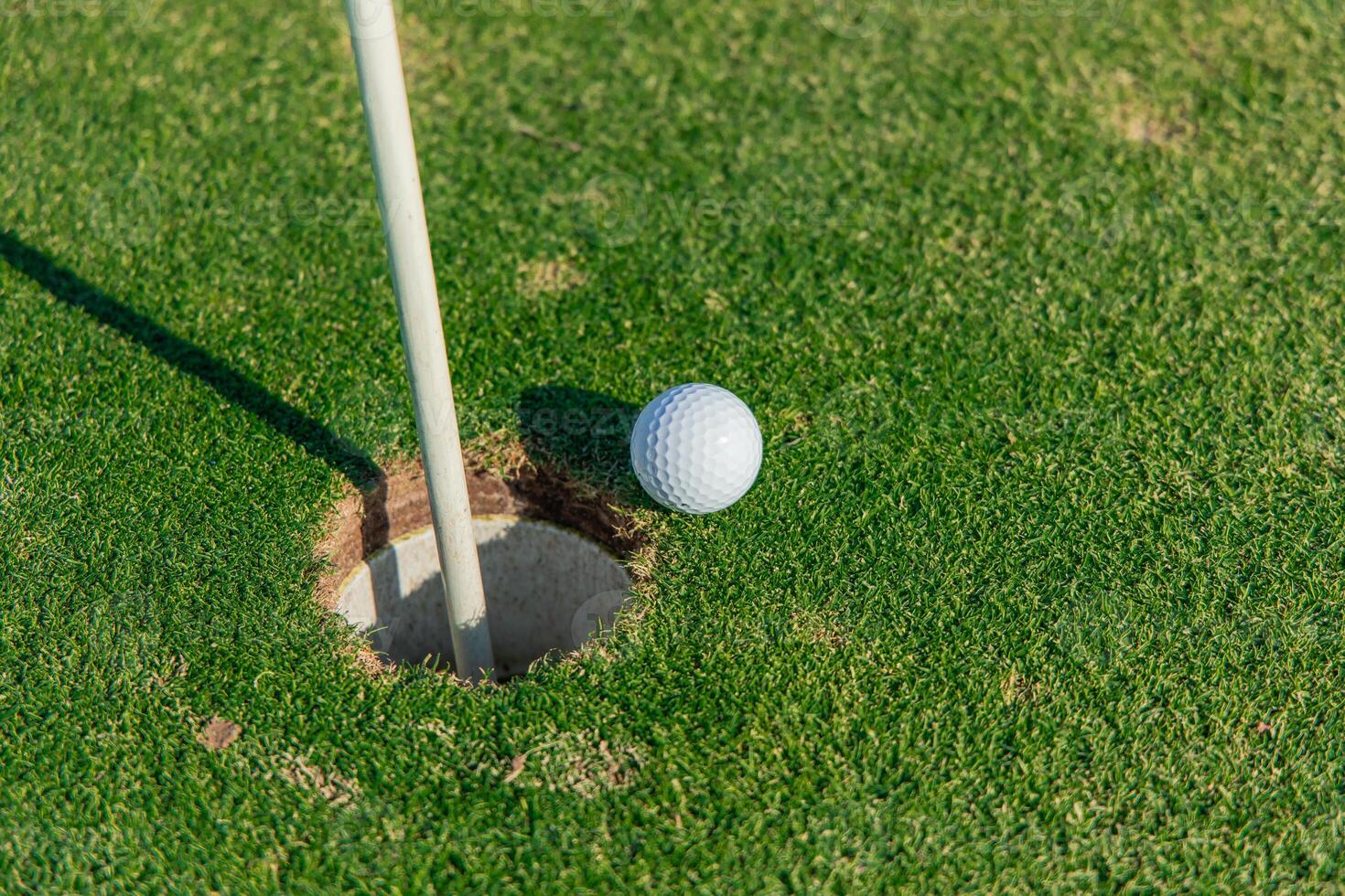 Close-up of a golf ball on the edge of the hole on the green photo